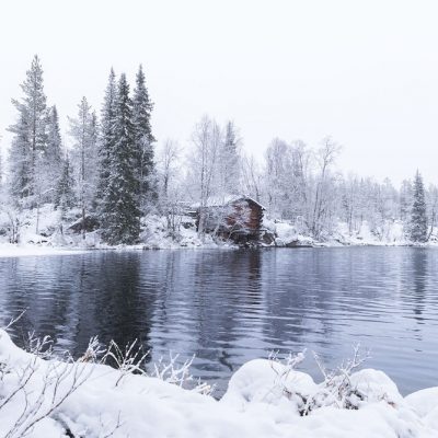 A small cabin along a wild river in Finnish Lapland during winter