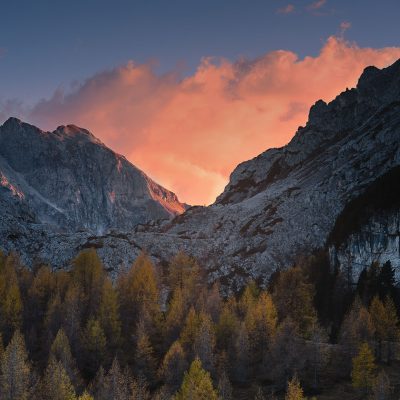 The sun setting behind the moutain range in Dolomites and litting up clouds