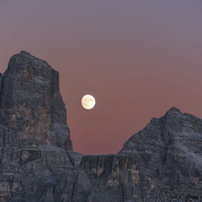 A close up to the Moon rising between two moutains in Dolomites