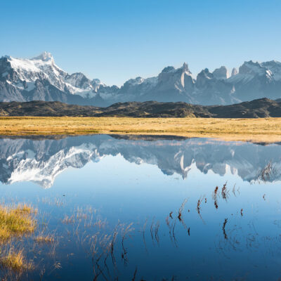 Perfect reflection of Torres del Paine mountain range on a clear sky Fall day