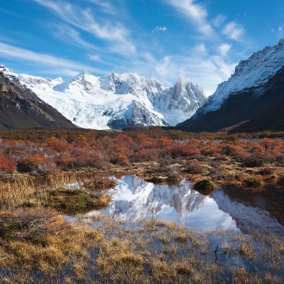 Cerro Torre reflecting in a pond surround by trees with golden leaves