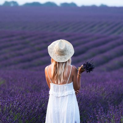 A woman with a bouquet of lavender in a lavender field. Model: lesdroners.fr